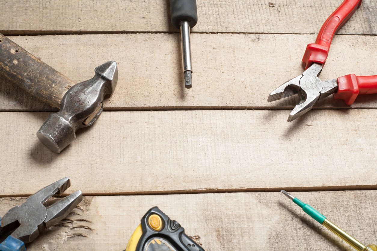 Hammer, pliers and hand tools on a wooden workbench