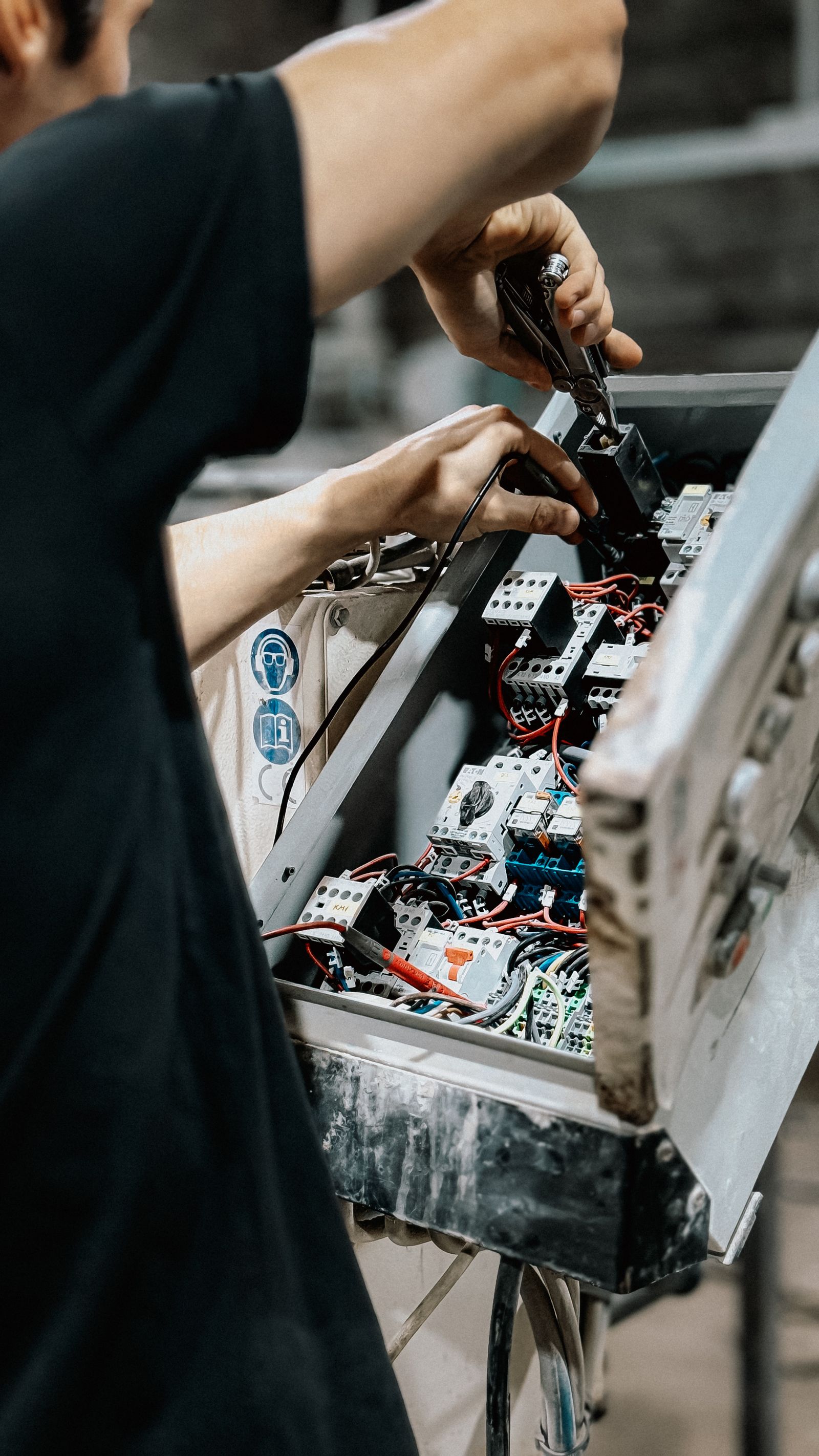 Technician adjusting wiring inside an electrical control panel