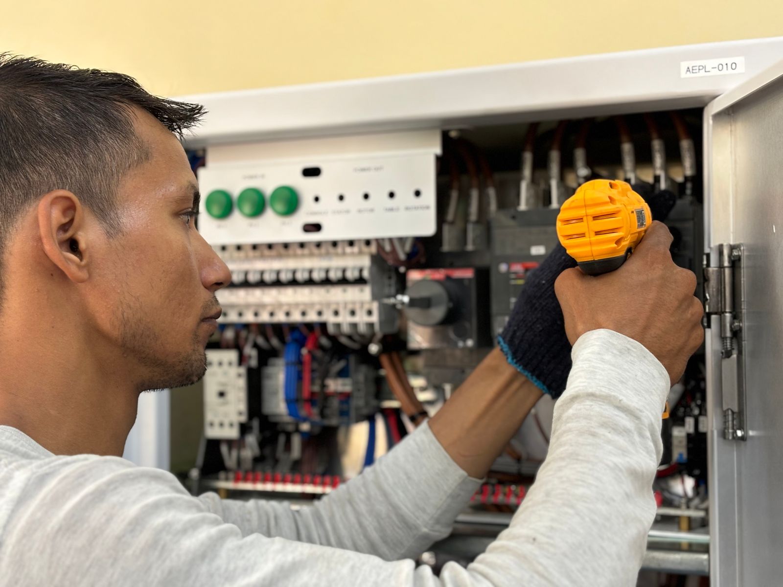 Electrician using a drill while working on an electrical panel
