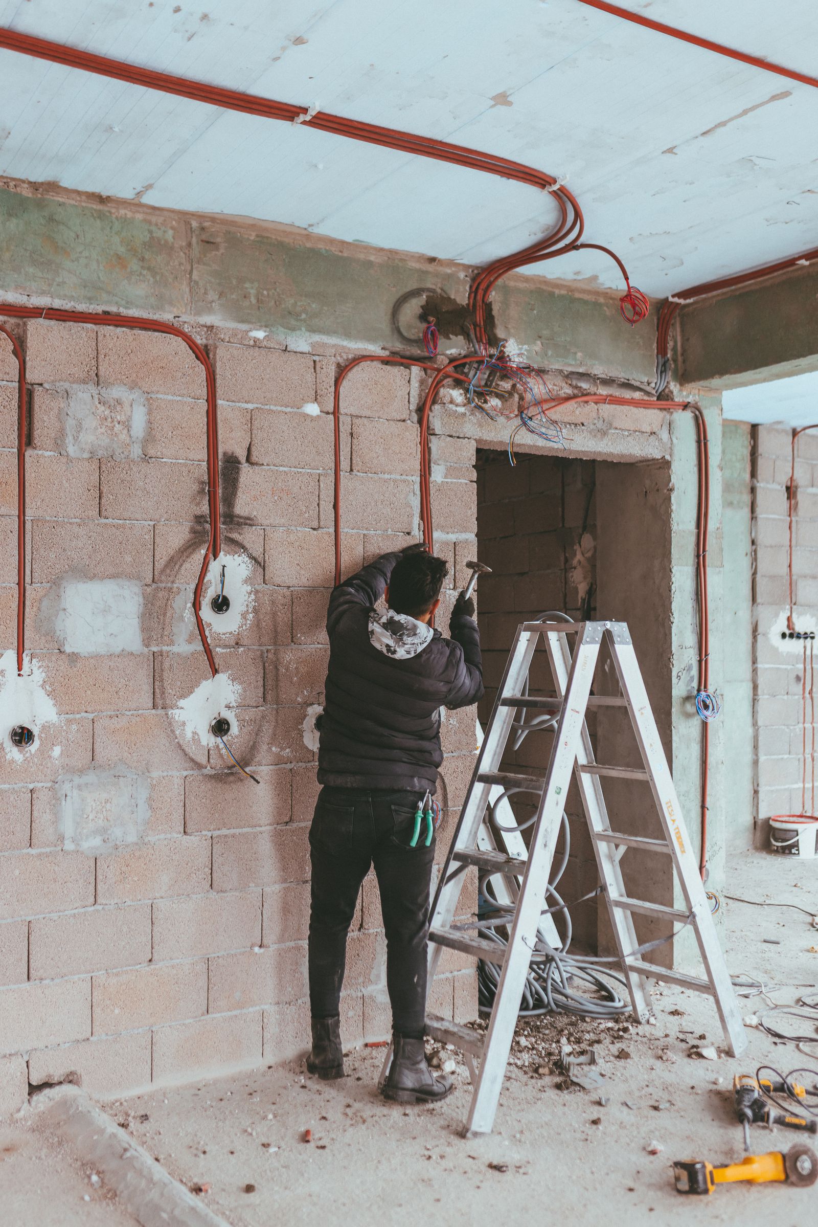 Electrician roughing in wiring and lighting in a room under renovation
