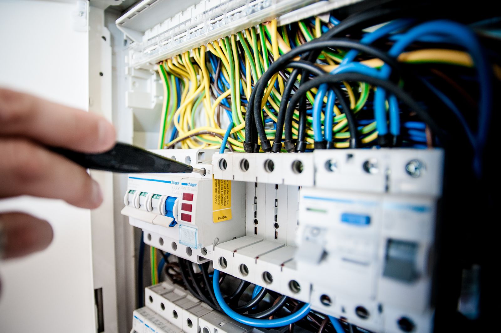 Hand working on breakers in an electrical switchboard